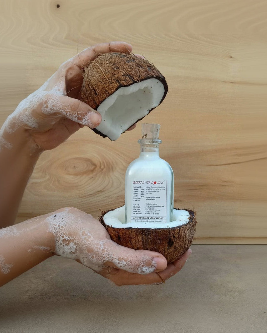 Bottle of coconut oil in a half-coconut shell held by hands with coconut pieces.