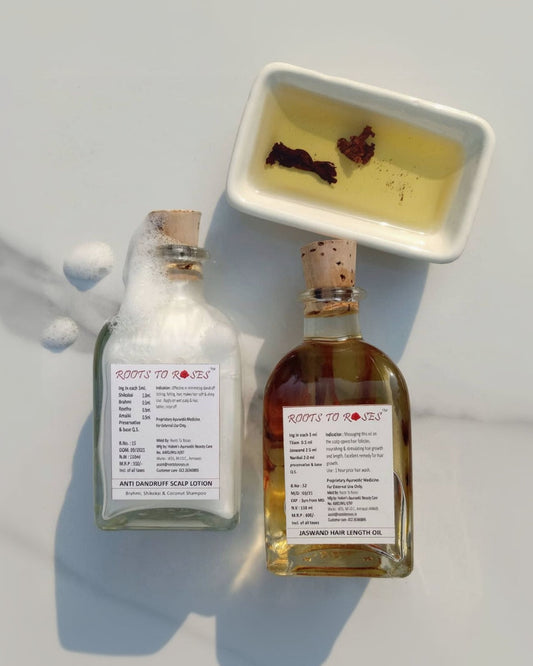 Two glass bottles, one with a label reading 'JASWAND HAIR LENGTH OIL' and the other with a label reading 'COCONUT SHAMPOO'. Both bottles are filled with liquid and have wooden caps.