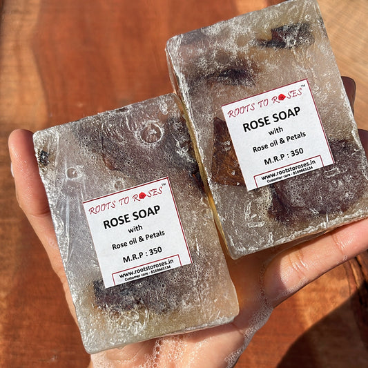 Two bars of rose soap held in a hand with visible branding and product details.