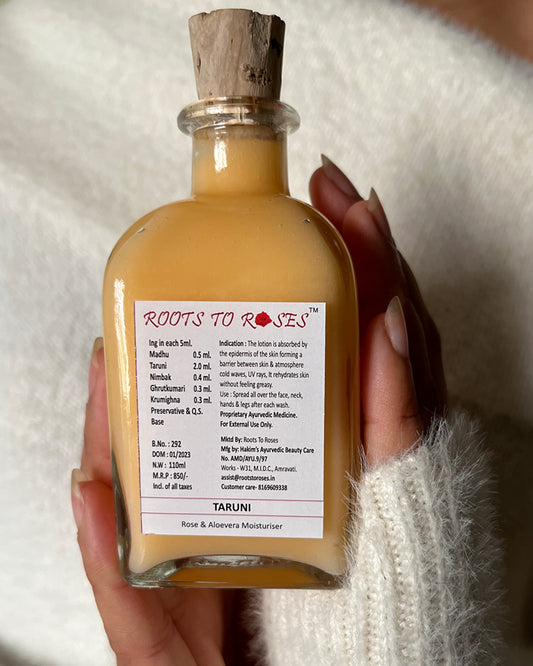 Bottle of 'Roots to Roses' product held by a person with a white textured background