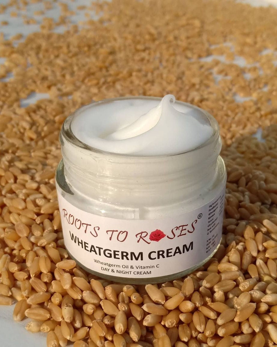 A jar of Wheatgerm cream by Roots to Roses, surrounded by wheat grains. The label on the jar reads 'Wheat to Roses Wheatgerm Cream' with additional text that includes 'Roots to Roses', 'Wheat & Rose', 'Germ & Blossom', and 'With Vitamin C'.